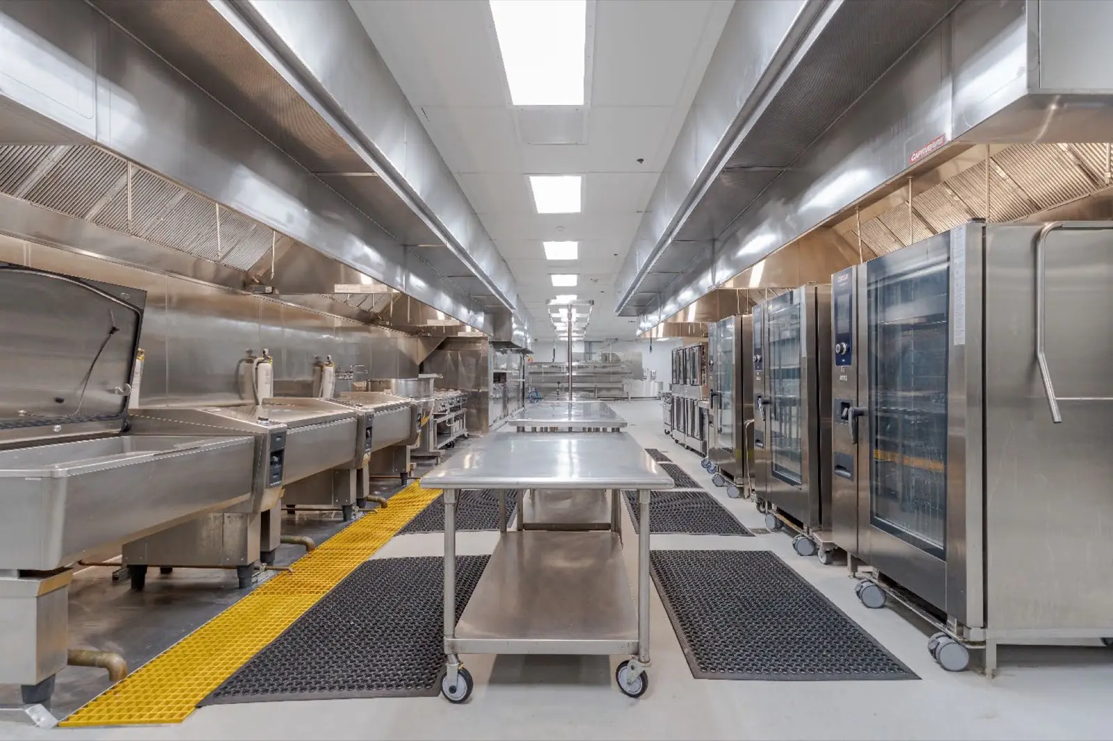 Stainless commercial kitchen with hood vents and convection ovens