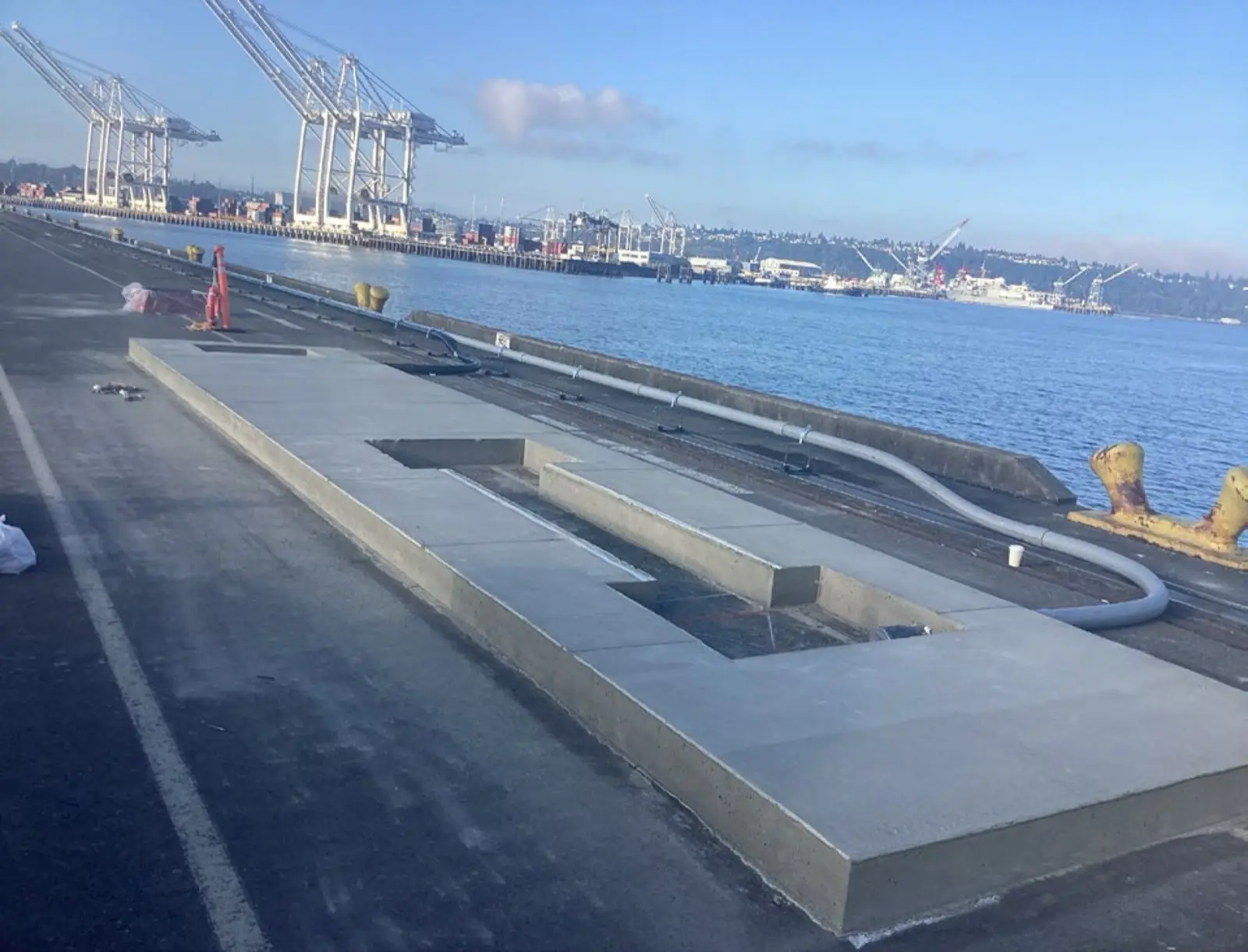 Waterfront concrete pad with port cranes and harbor in background