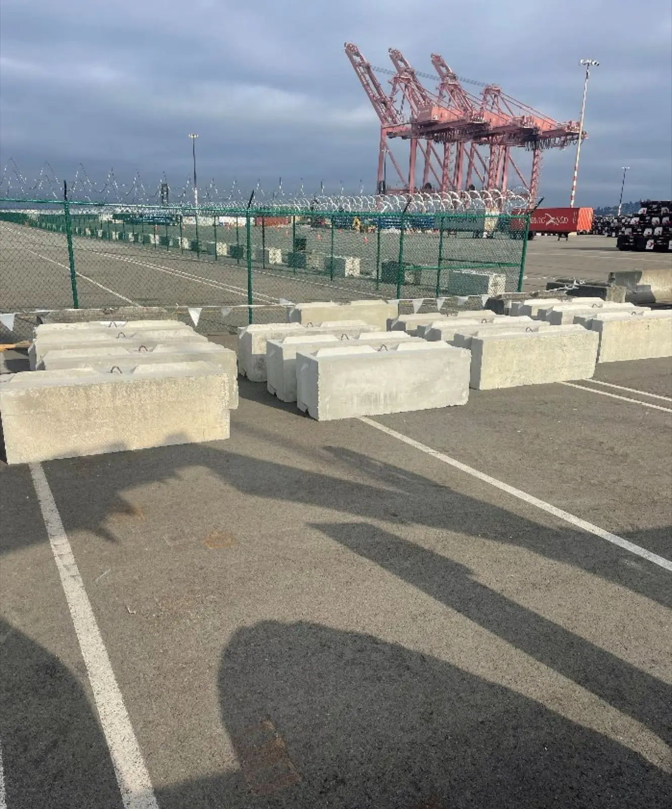 Concrete storage blocks staged at industrial port with red cargo cranes